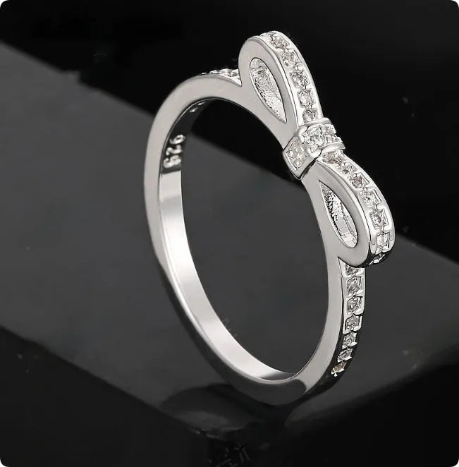 Silver electroplated ring with a detailed bow shape and set zircon crystal accents.