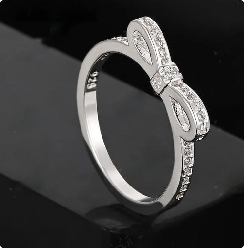 Silver electroplated ring with a detailed bow shape and set zircon crystal accents.