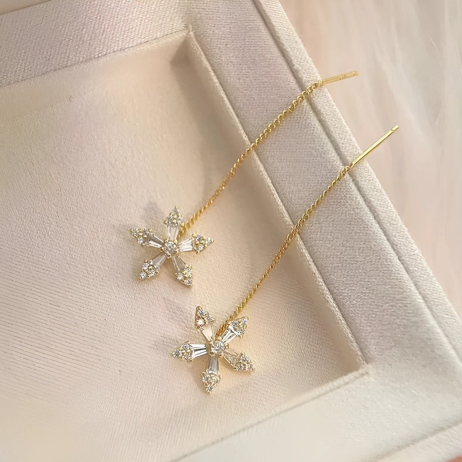 Long gold drop earrings for women with metal construction and secure fastening on white background