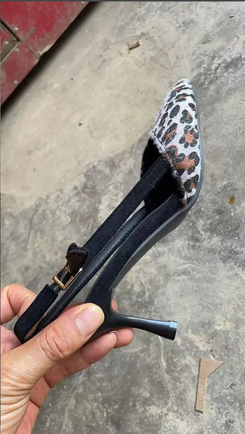 Women's leopard print suede sandals with a pointed toe and high heel on a neutral background.