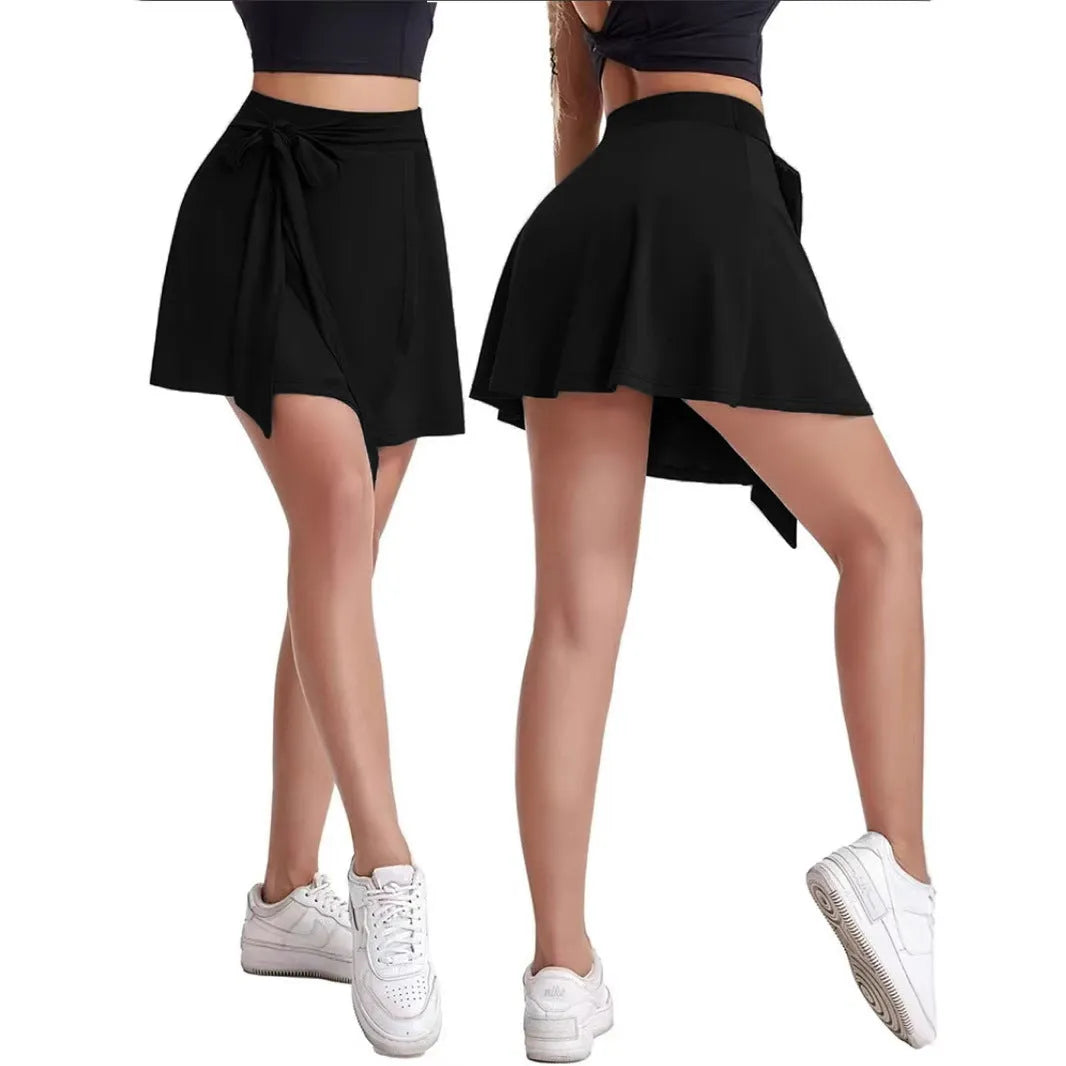 Black thigh-length sports skirt with high waist and built-in shorts, featuring shoulder strap detail and culotte silhouette