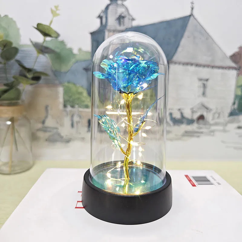 Small decorative night lamp with glass cover, plastic flower, and black base on a pink box.