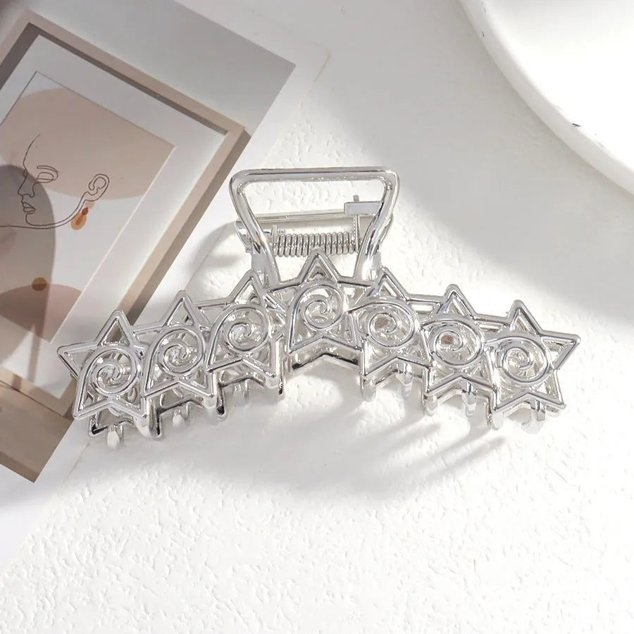 Assorted silver metal hair claws and barrettes including wave, knot, bow, and pearl designs on a white background.