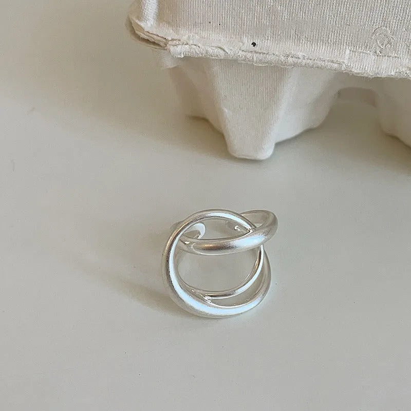 Geometric open ring with three-dimensional interlaced metal design in gold or silver colour