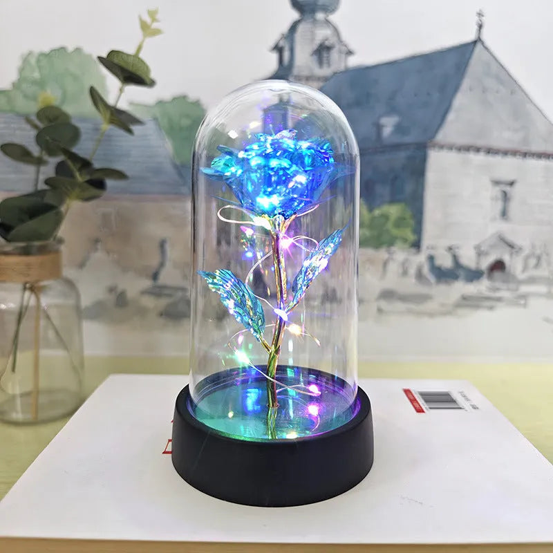 Small decorative night lamp with glass cover, plastic flower, and black base on a pink box.