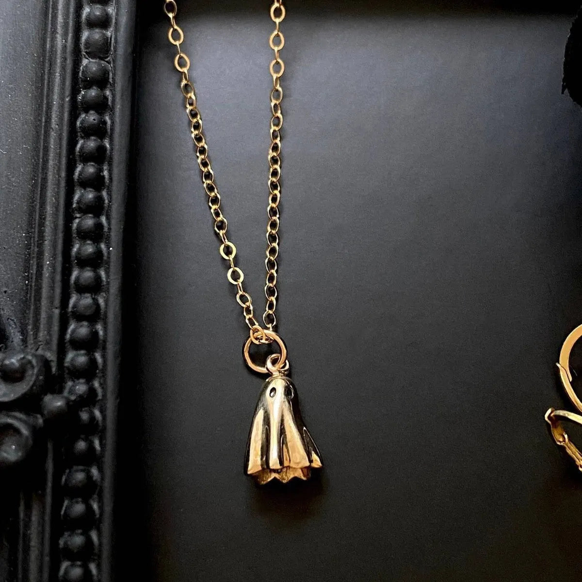 Close-up of a titanium steel ghost pendant on a stainless steel chain necklace.