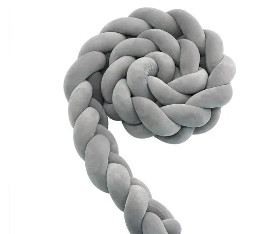 Braided knot crib bumper in spandex velvet, shown bending to fit a white wooden cot.