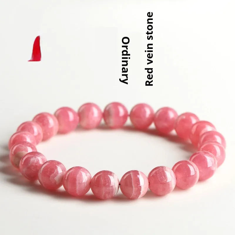 Women's geometric crystal bracelet with red rhodochrosite stone and a Longevity Lock charm on a wrist.