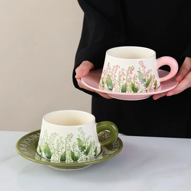 Ceramic coffee cup and saucer set for two with matching spoons in bell-shaped design