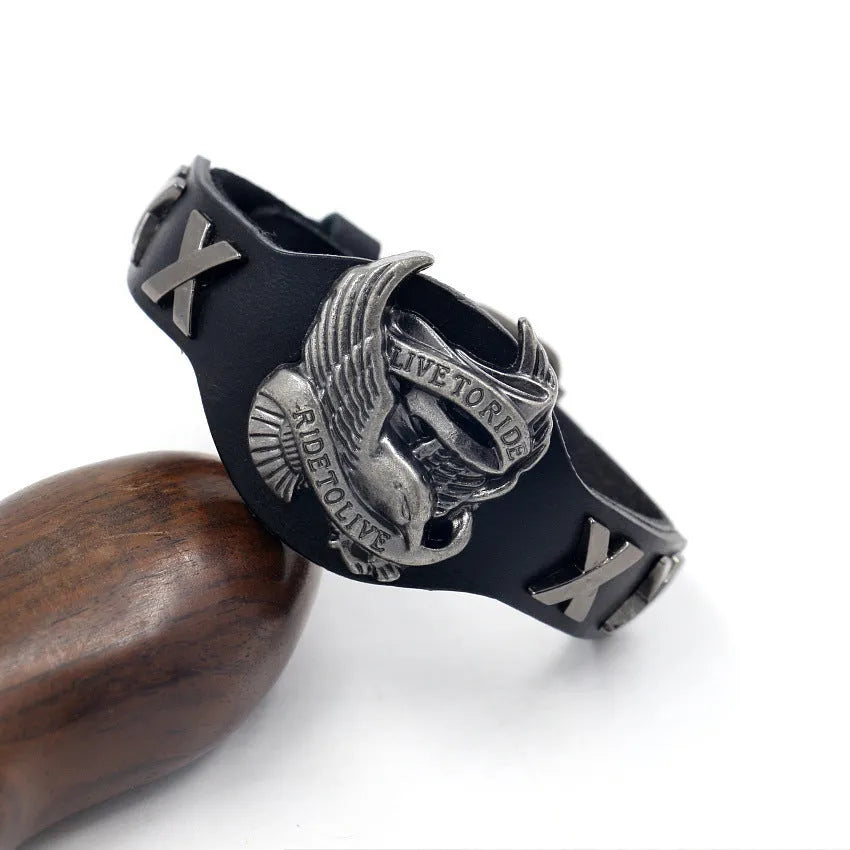 Black leather bracelet with an alloy eagle decoration and watch-button clasp on a wrist.