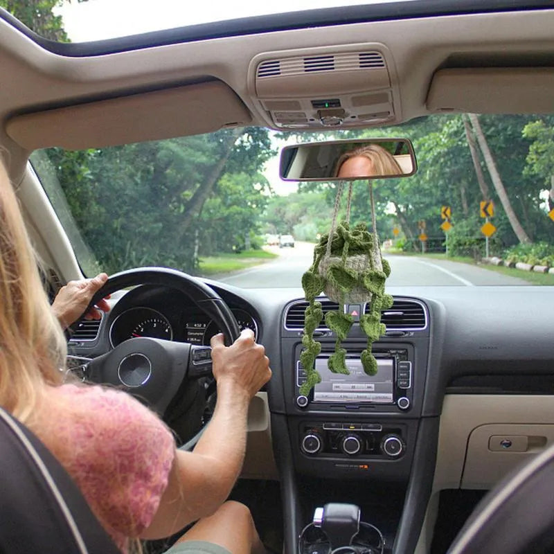 Green and white knitted wool car plant decoration with macramé texture and a white hanging rope.