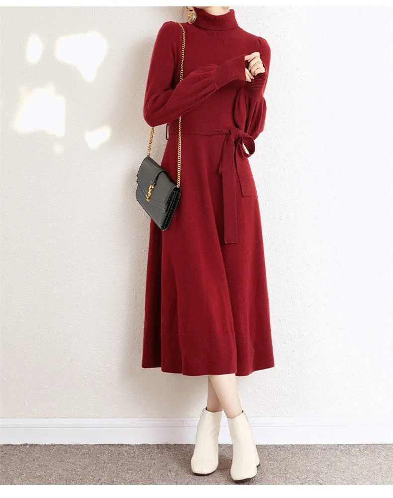 A rose red turtleneck knit dress with long sleeves, an elastic waist, and a loose mid-length skirt on a hanger.