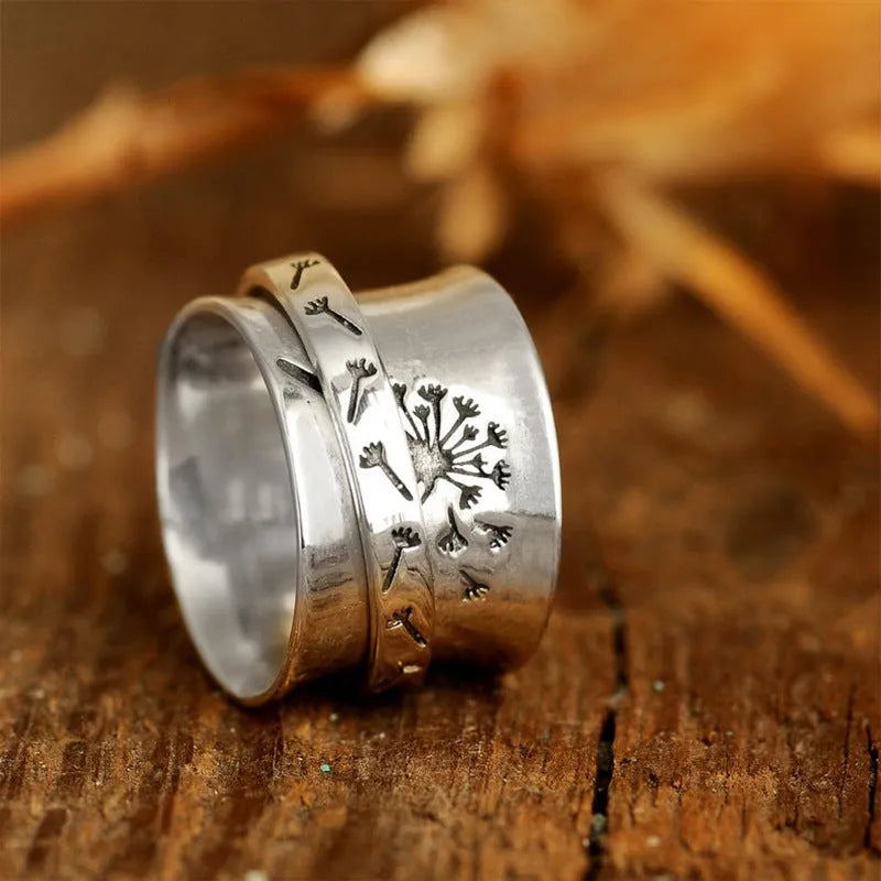 Silver-coloured rotatable flower ring on a finger, showing the floral detail.