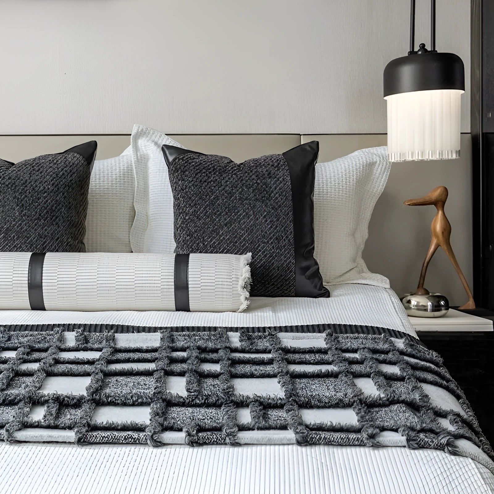Modern minimalist grey and white plaid bed runner blanket with matching pillowcase and round pillow on a double bed.