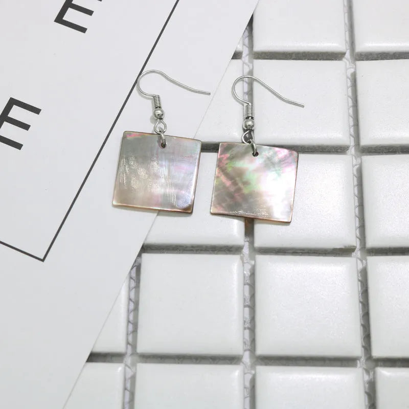 A pair of geometric-shaped earrings made from shell in a retro style, showing colour options.