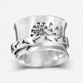 Silver-coloured rotatable flower ring on a finger, showing the floral detail.