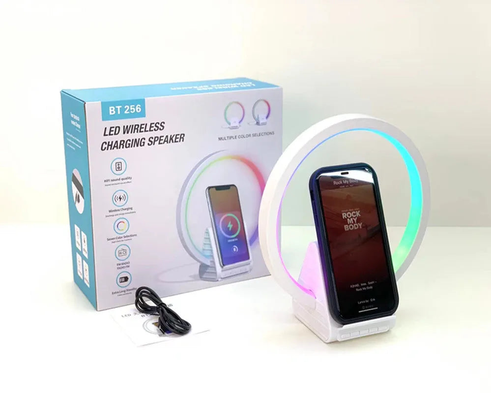White smart Bluetooth speaker with wireless charging pad and ambient lighting on desktop