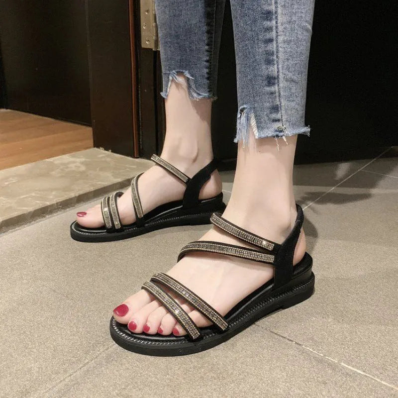 Women's silver flat sandals with rhinestone decoration and an elastic band, showing the round toe and rubber sole.