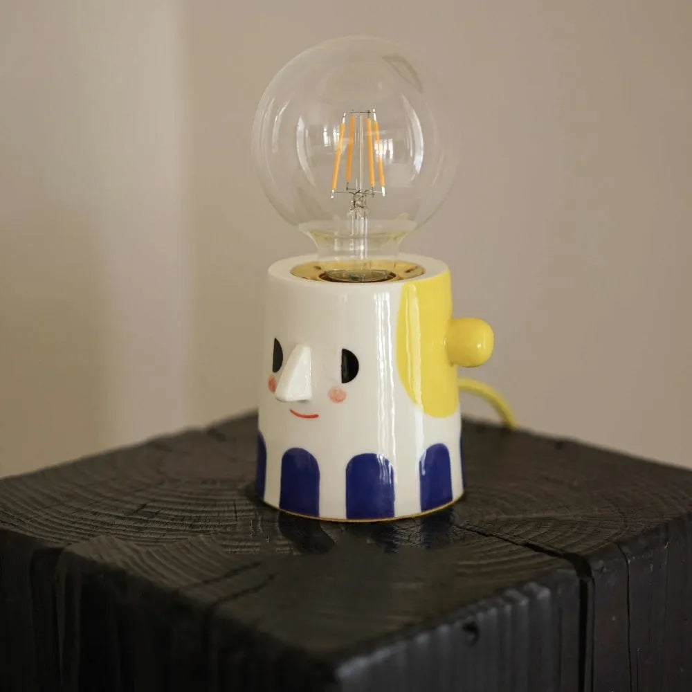 Handmade ceramic table lamp with ball headlight design on a bedside table