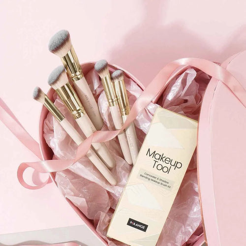 Angled apricot blusher brush and four other synthetic makeup brushes on a white surface.