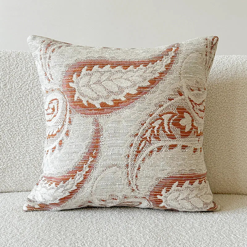 American-style jacquard pillow cover with paisley and flower pattern in amber colour, shown on a sofa.