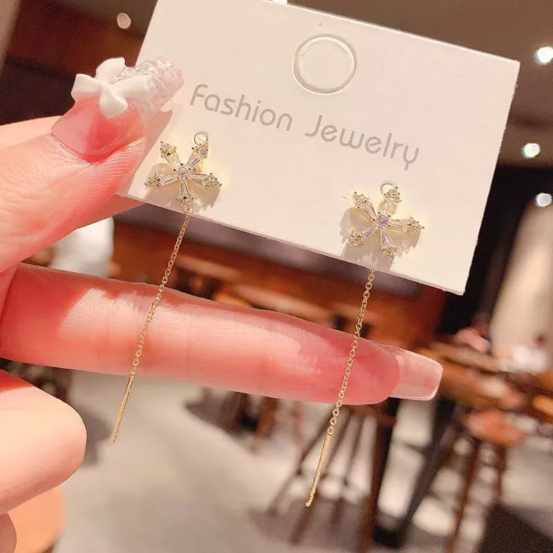 Long gold drop earrings for women with metal construction and secure fastening on white background