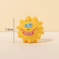 Set of four coloured latex squeaky dog balls with cute faces on a bumpy surface.