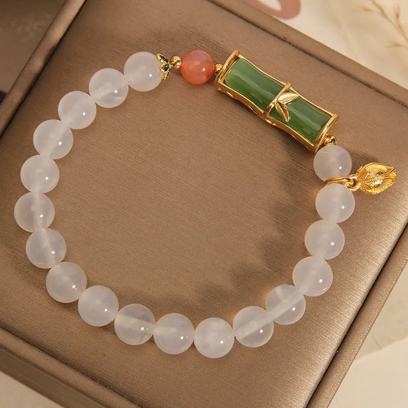 Women's white agate and jade bamboo joint beaded bracelet on a wrist.