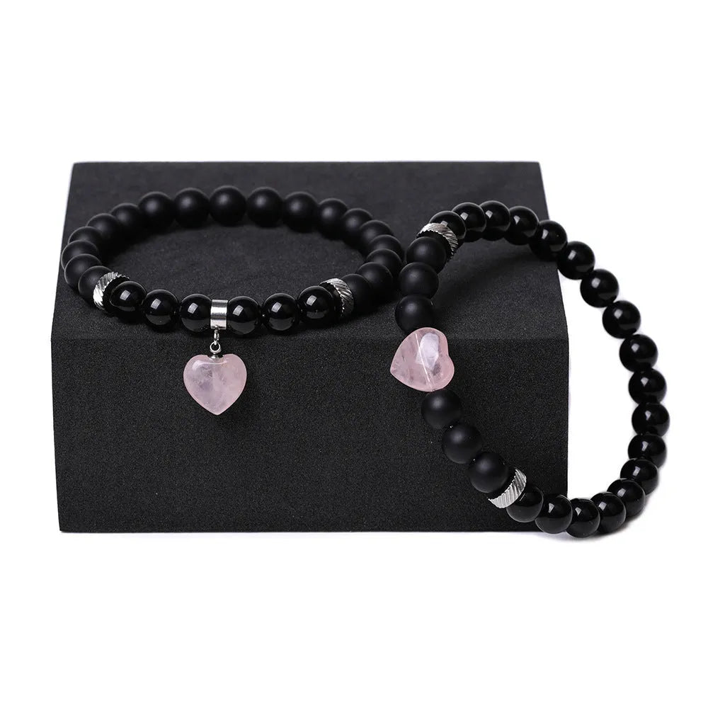 A pair of matching bracelets with polished geometric heart pendants made from natural stone.