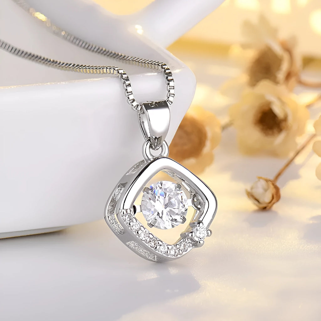 Silver heart pendant necklace with small crown and bow charms on a delicate chain.