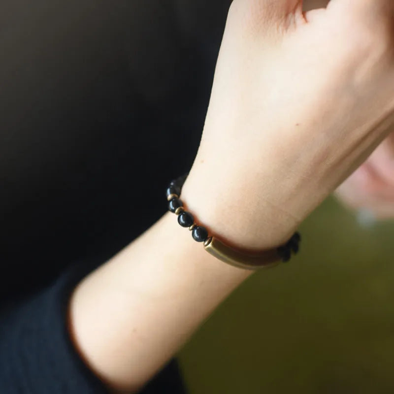 Layered retro ethnic bracelet with natural stone beads and antique brass details on a wrist.