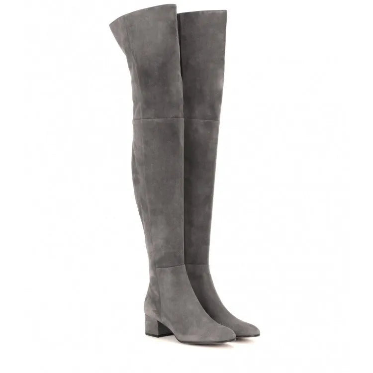 Women's grey suede over the knee flat boots with a low thick heel and pointed toe on a neutral background.