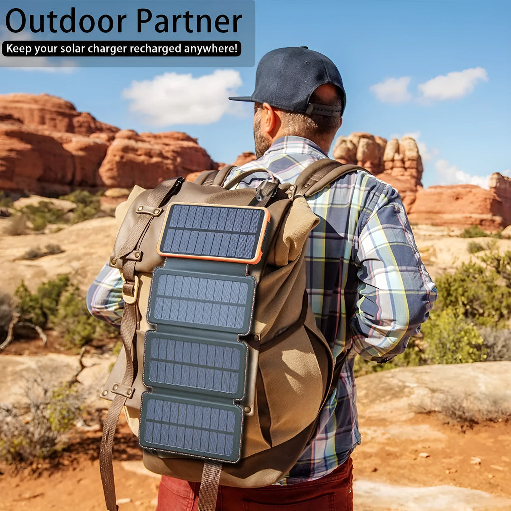 Black solar power bank with a solar panel, showing its USB ports and LED light, placed outdoors on a rock.
