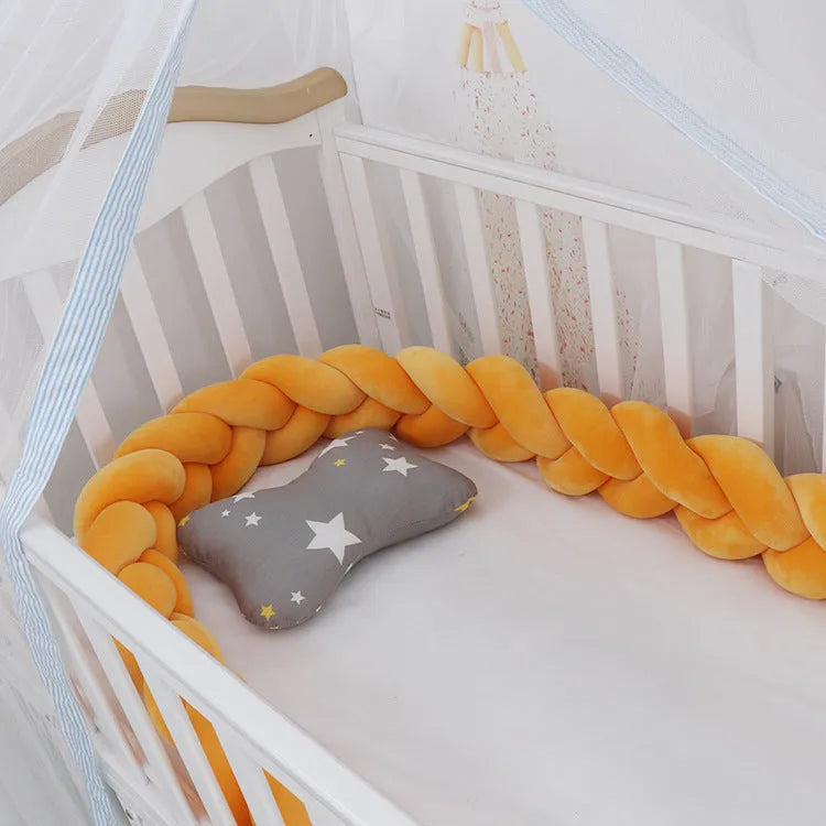 Braided knot crib bumper in spandex velvet, shown bending to fit a white wooden cot.