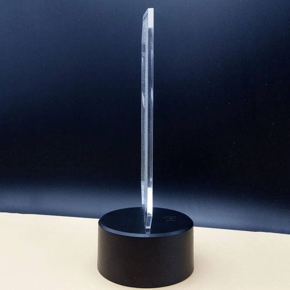 3D acrylic LED desk lamp showing colourful light projection with remote control on a wooden table.