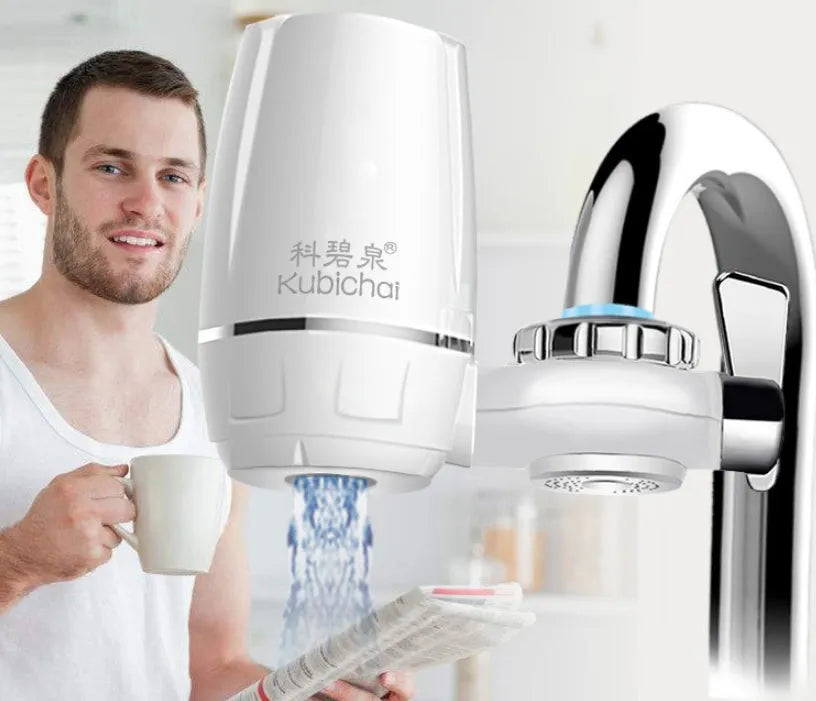 White plastic kitchen tap water filter with ceramic cartridge and universal adapter kit on a counter.