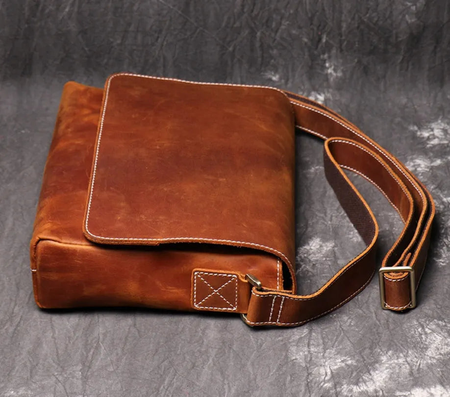 Men's vintage brown leather messenger bag with adjustable strap, shown open to reveal internal organiser pockets.