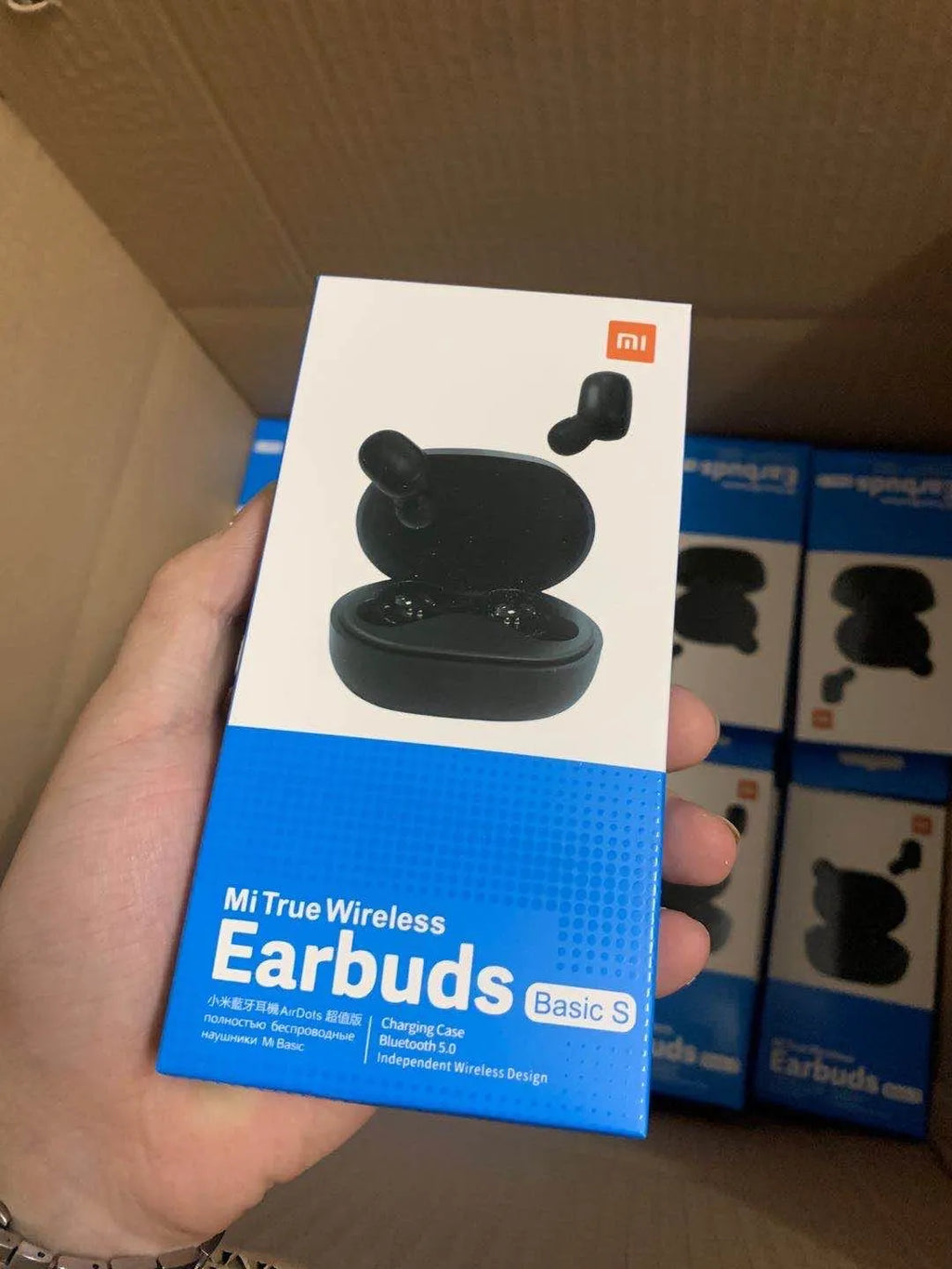 Redmi AirDots black true wireless earbuds next to their white charging case.