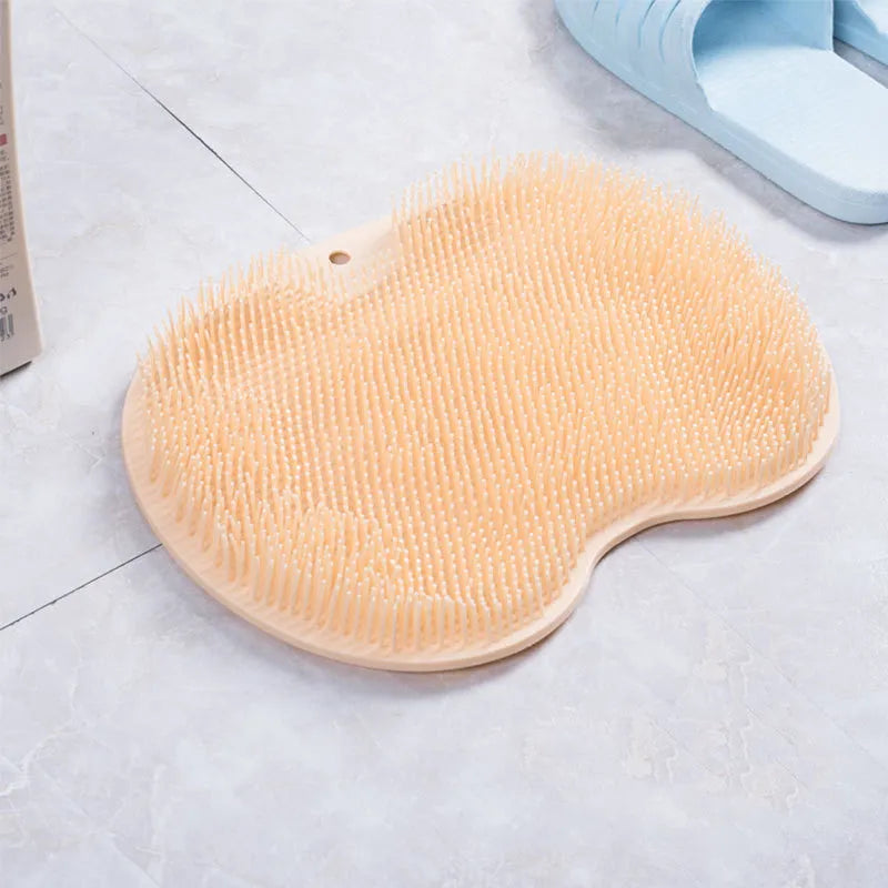 Orange TPR bath brush with silicone bristles and suction cups on base, shown on bathroom tiles.