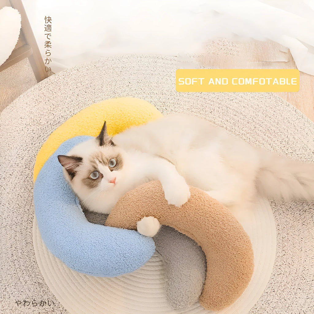 Blue U-shaped cat pillow with an integrated adjustable fabric collar on a grey blanket