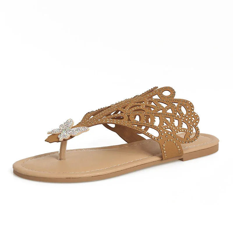 Women's black slip-on sandals with rhinestone accents and a hollow-out design on a flat rubber sole.