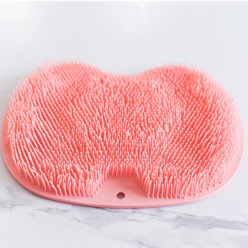 Orange TPR bath brush with silicone bristles and suction cups on base, shown on bathroom tiles.