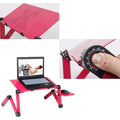 Adjustable black laptop stand desk with mouse pad and USB cooling fan, folded for storage, on a wooden floor