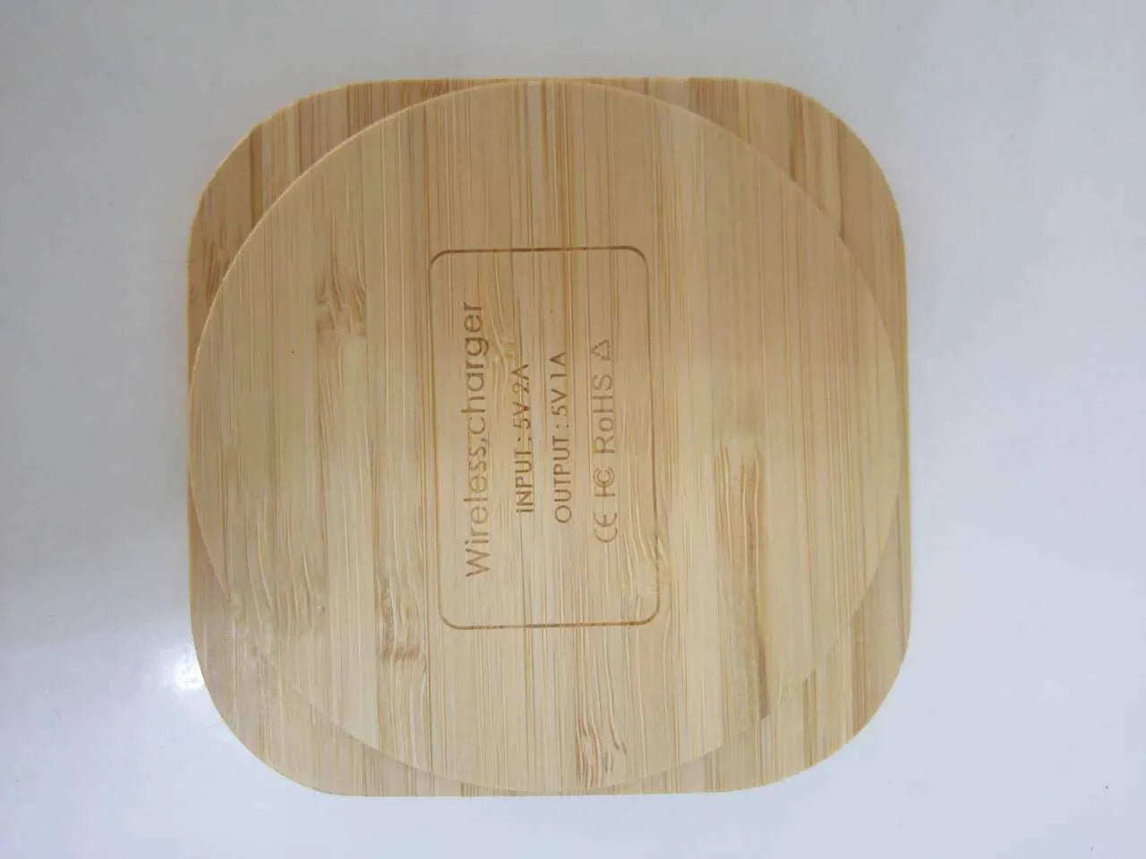 Square wooden bamboo 5W Qi wireless charging pad for smartphones on a table.