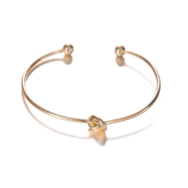 Gold women's vintage cuff bracelet with arrow knotted design on wrist