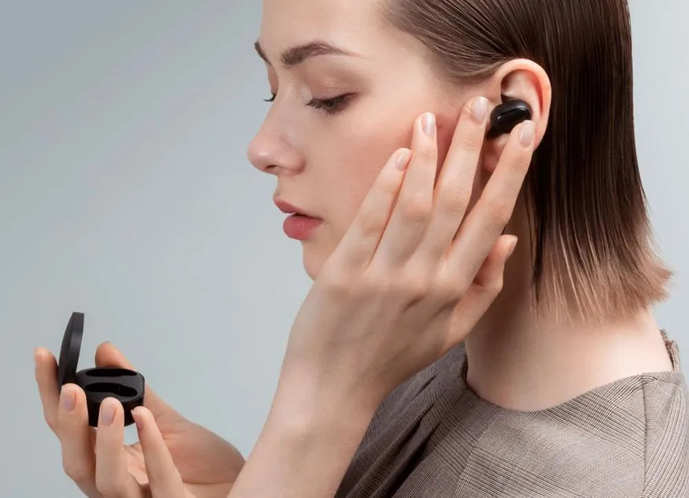 Redmi AirDots black true wireless earbuds next to their white charging case.