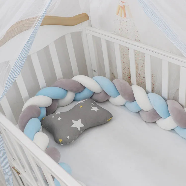 Braided knot crib bumper in spandex velvet, shown bending to fit a white wooden cot.