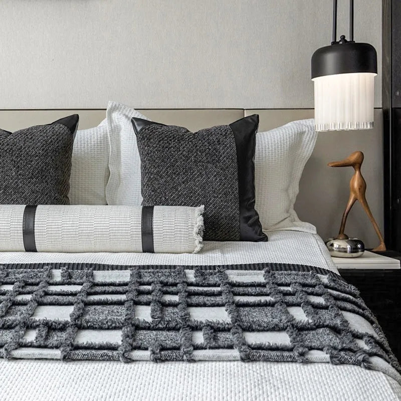 Modern minimalist grey and white plaid bed runner blanket with matching pillowcase and round pillow on a double bed.