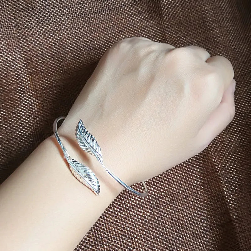 Silver metal bangle bracelet with open cuff design, 6.3cm diameter, on white background