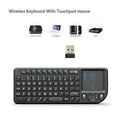 Black wireless mini keyboard with built-in trackpad and 2.4GHz receiver on a desk